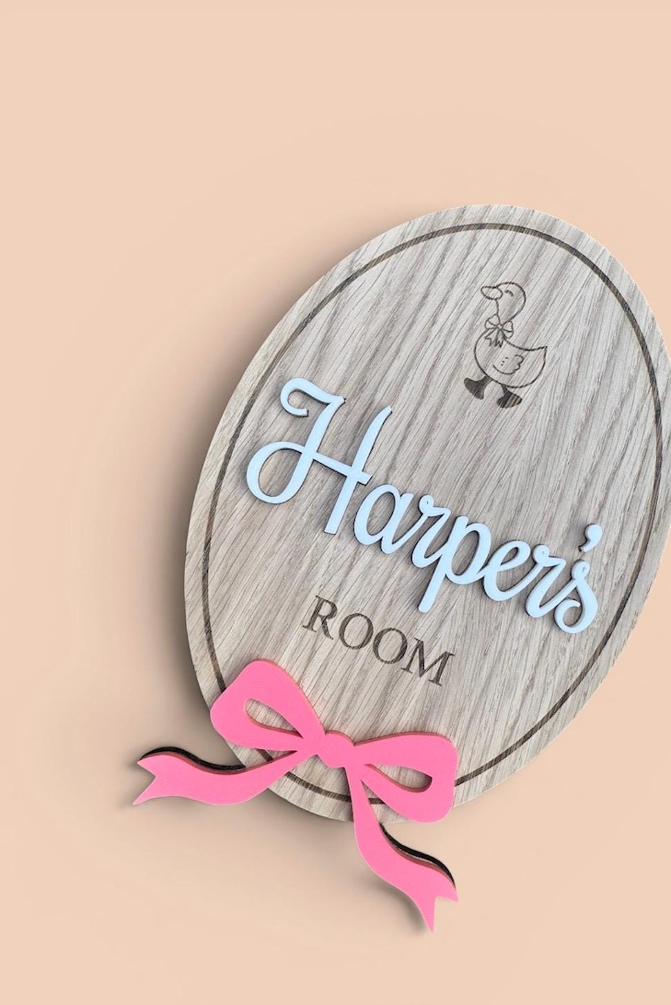Personalised wooden name plaque for kids bedrooms or nursery rooms, featuring a lovely oak veneered finish with laser engraved details. Customised with your child’s name, with the name and bow laser cut from acrylic. Available in different colour options and ideal as a baby shower, birthday, or nursery gift.