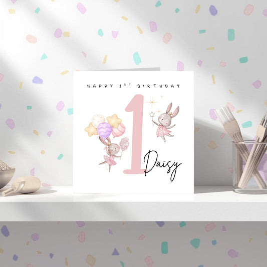 May include: A birthday card with the text "Happy 1st Birthday" and the name "Daisy". The card features illustrations of bunnies, balloons, and the number 1 in pink.