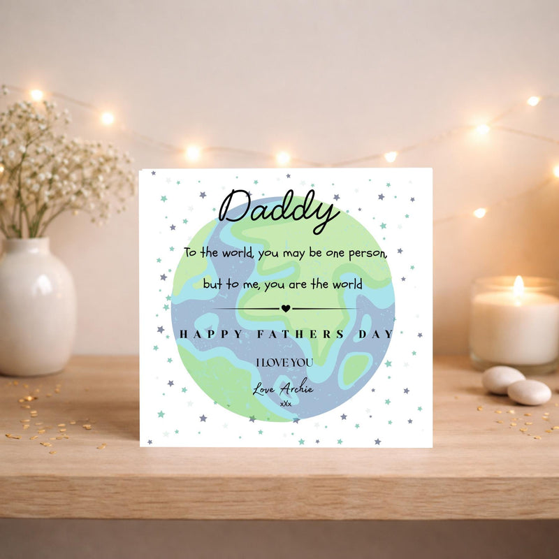 May include: A Father's Day card featuring a globe design with the word "Daddy" in cursive. The card includes the message "Happy Fathers Day, I love you" and is signed "Love Archie". The background is decorated with small stars.